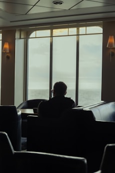 A calm young man sitting peacefully in a cozy room with soft natural light.