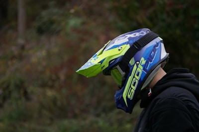 A rider gearing up with a vibrant yellow motocross helmet under industrial lighting.