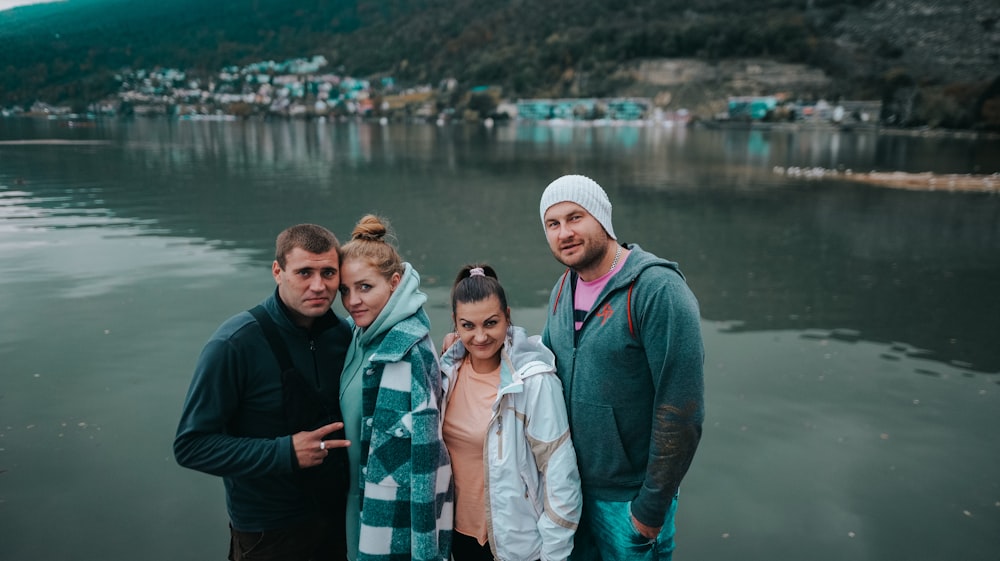 a group of people posing for a photo in front of a body of water