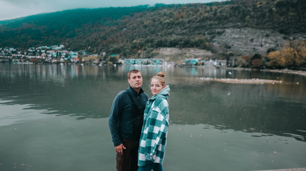 a man and woman standing in front of a body of water