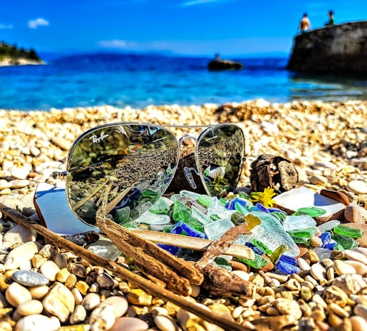 Sunglasses placed on a beach towel with the sea in the background, highlighting water resistance.