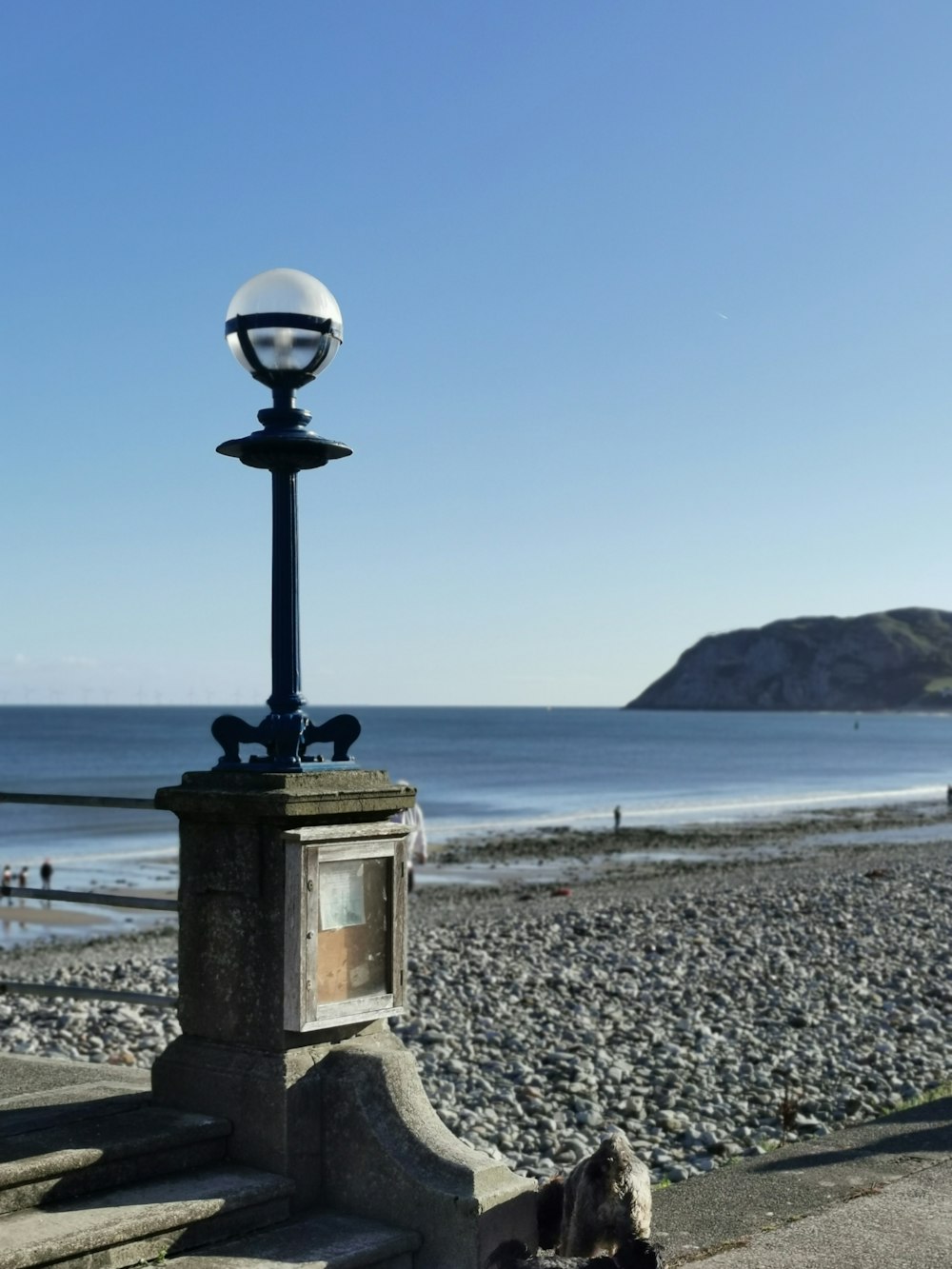 a lamp post on a rocky beach