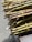 Bundles of green and brown sugarcane stalks are tied together with yellow twine, resting on a wooden surface. The stalks are neatly cut and highlighted by natural sunlight.
