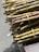 Bundles of green and brown sugarcane stalks are tied together with yellow twine, resting on a wooden surface. The stalks are neatly cut and highlighted by natural sunlight.