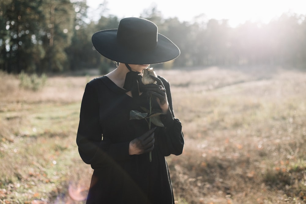 a person in a black hat and coat holding a gun