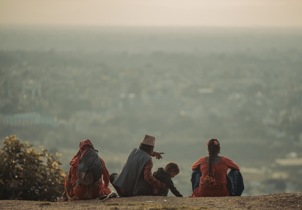 a group of people sitting on a hill overlooking a valley