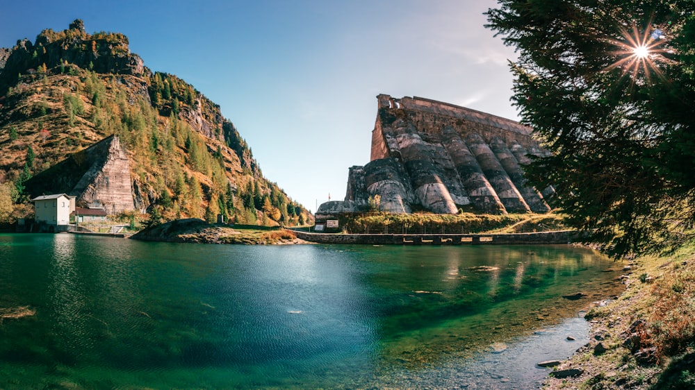 a body of water with a rocky cliff and trees on the side