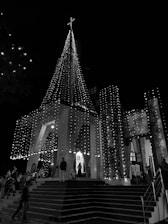 A warm evening scene of the synagogue lit up, welcoming congregants inside.