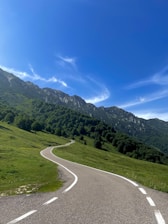 A winding road through a lush green landscape under a clear blue sky.