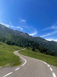 A winding road through a lush green landscape under a clear blue sky.