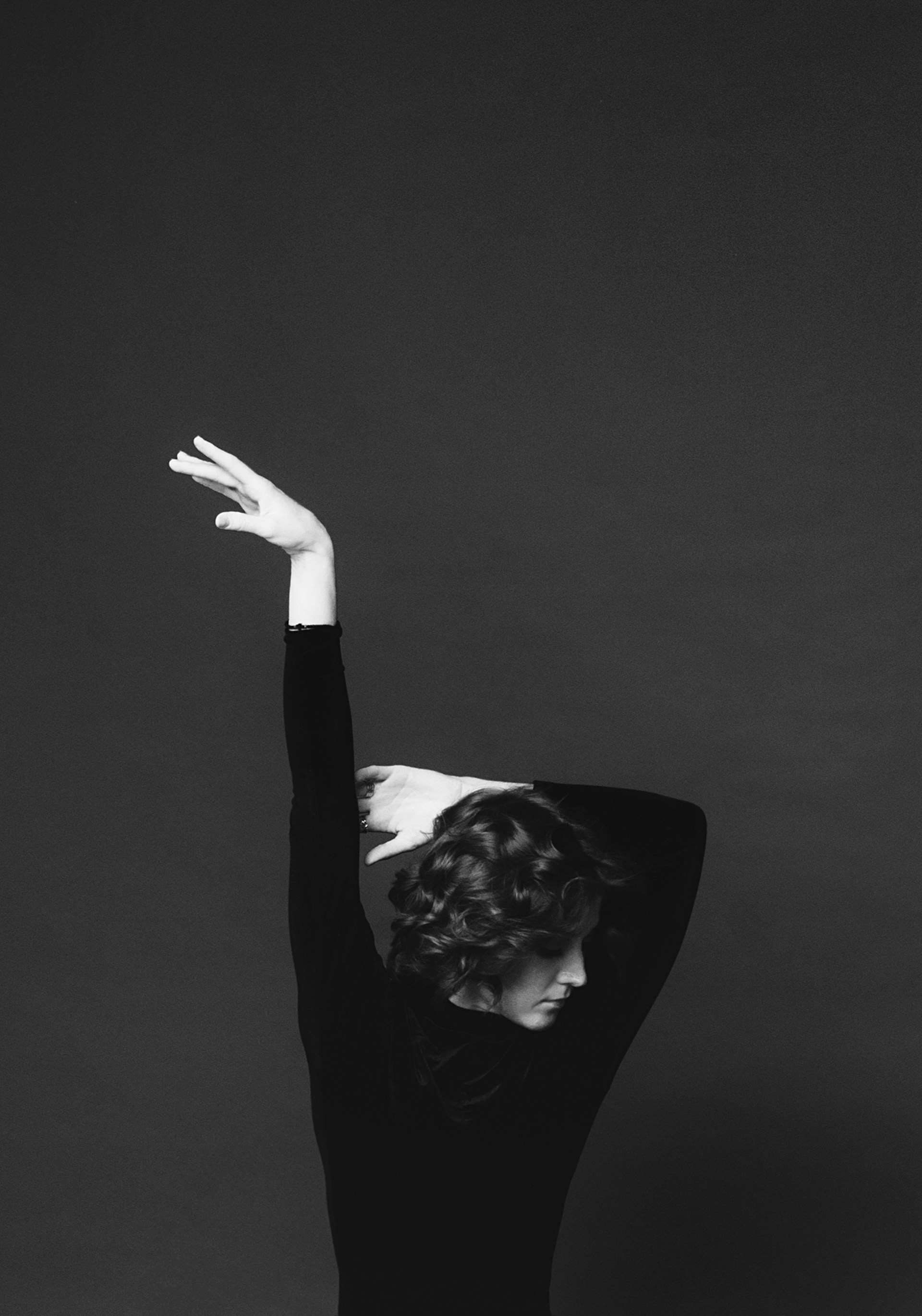 An elegant side profile of a woman showcasing glossy, well-maintained curly hair cascading over her shoulder.