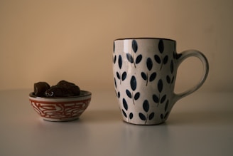 a cup of coffee next to a bowl of cereal