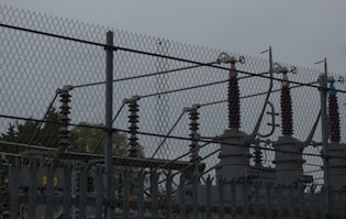 a fence with a metal gate and trees in the background