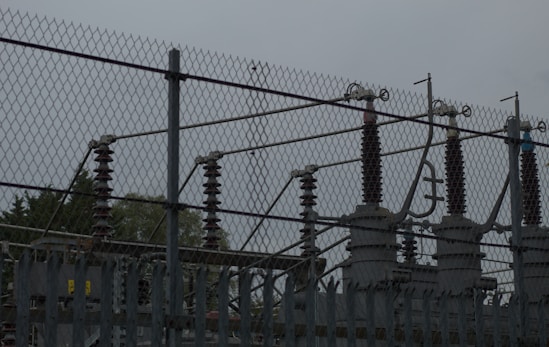 a fence with a metal gate and trees in the background