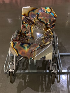 A wheelchair with spoke covers painted in a galaxy theme, showing stars and swirling nebulae under soft lighting.
