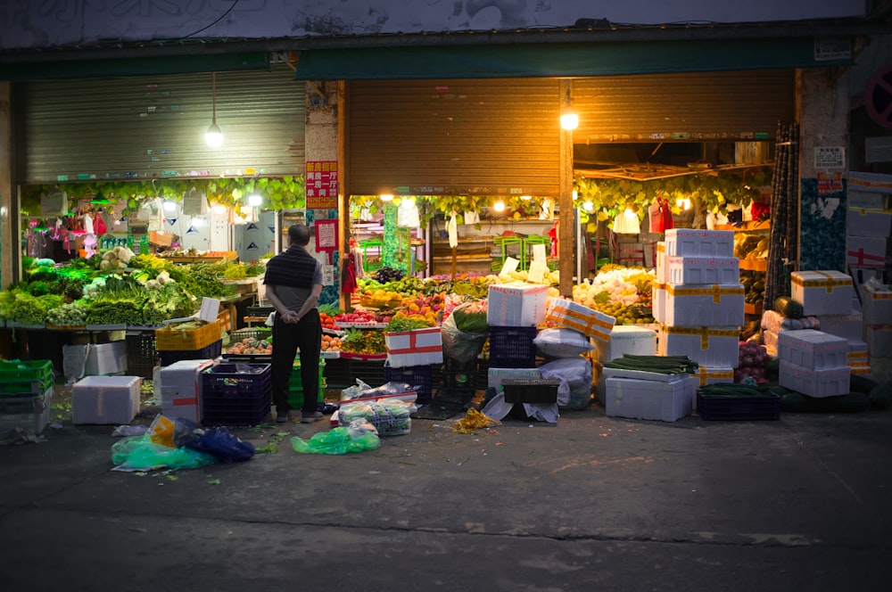 a person standing in front of a fruit stand