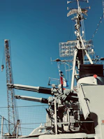 Close-up of a vintage naval gun turret on a warship with sailors preparing for battle.