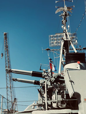 Close-up of a vintage naval gun turret on a warship with sailors preparing for battle.