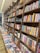 Rows of books neatly arranged on wooden shelves, featuring sections labeled nonfiction and classics. A long table displays various books lying flat, showcasing their covers.