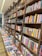 Rows of books neatly arranged on wooden shelves, featuring sections labeled nonfiction and classics. A long table displays various books lying flat, showcasing their covers.