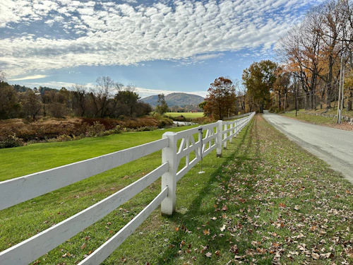 White wooden fence running beside a country road in Woodstock, Vermont