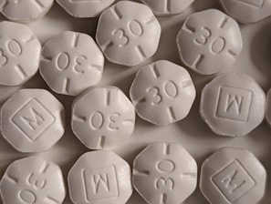 A close-up view of several round, white pills with an embossed '30' and 'M' in a square on them. The pills are arranged closely, partially overlapping.
