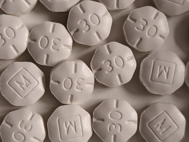A close-up view of several round, white pills with an embossed '30' and 'M' in a square on them. The pills are arranged closely, partially overlapping.