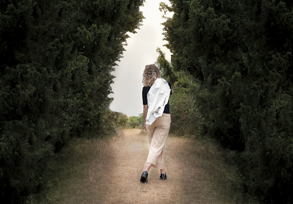 a man walking on a path between trees