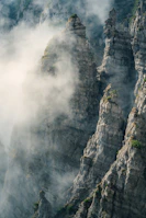 Dramatic rock formations and mist swirling around Chauli Ki Jali cliffs at dawn.