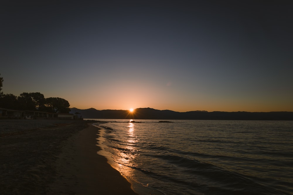 a beach with a body of water and a sunset