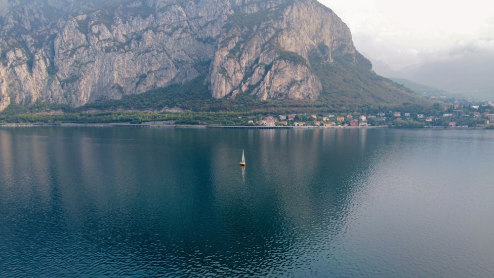a body of water with a sailboat in it and a mountain in the background