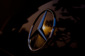 A close-up of a shiny Mercedes-Benz car part on a clean surface.