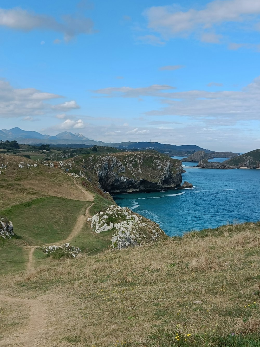 a body of water with land around it and a hill with a rock formation in the middle