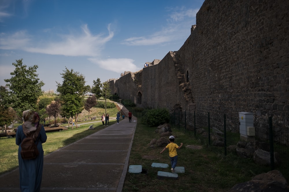 a person and a child walking on a path between stone buildings