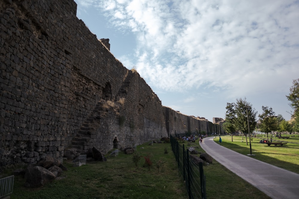 un mur de pierre avec une passerelle et de l’herbe et des arbres