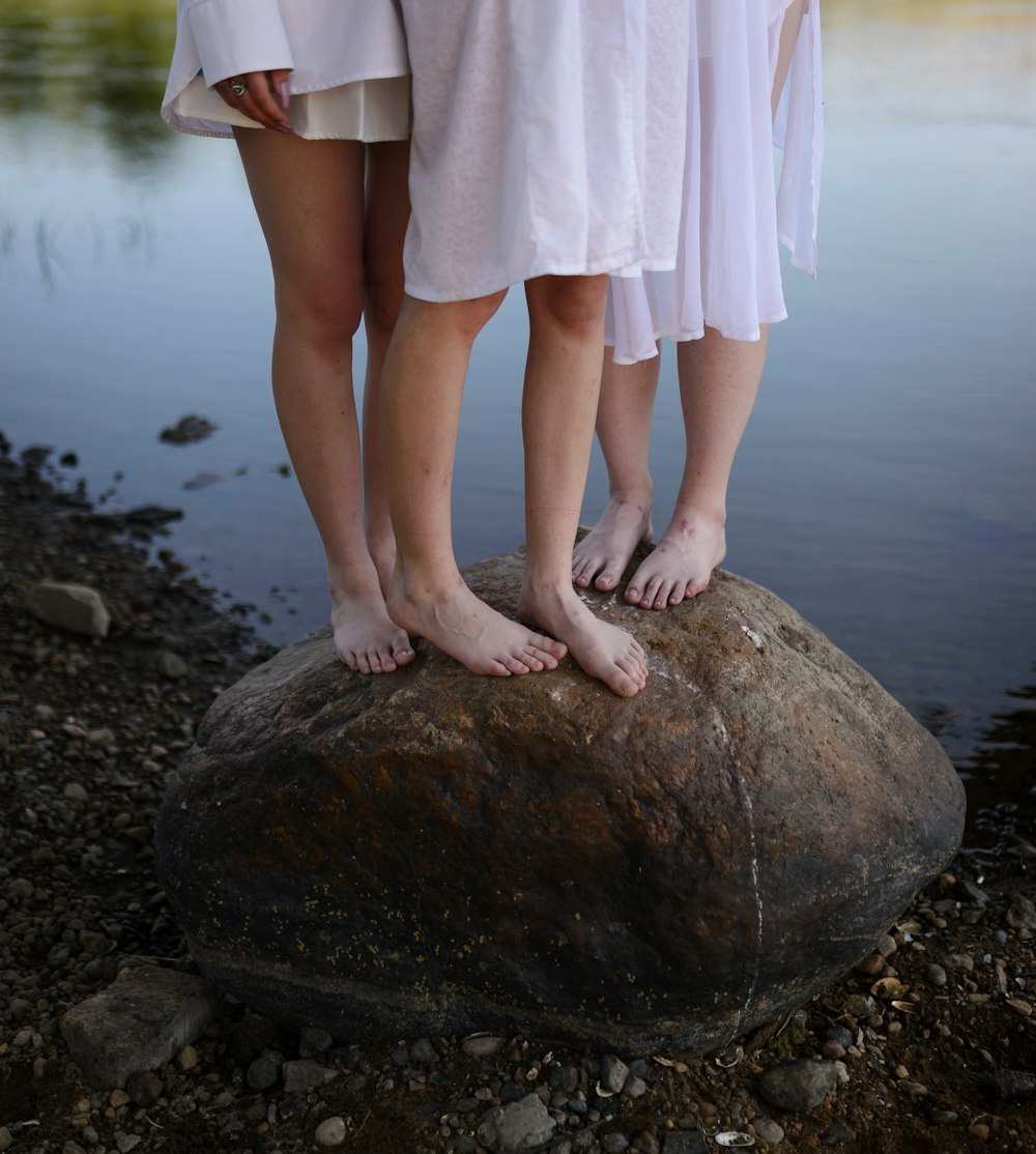 a pair of people standing on a rock in the water