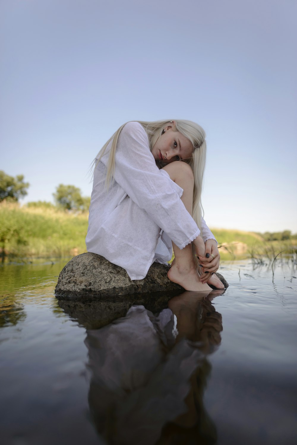 a person sitting on a rock in a body of water