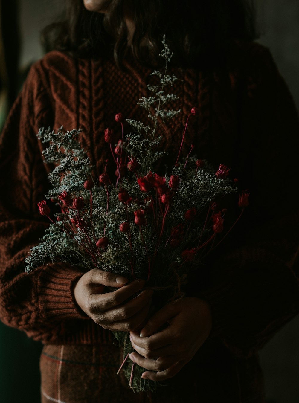 a person holding a bouquet of red flowers
