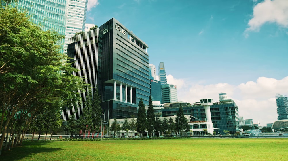 a large green field with buildings in the background