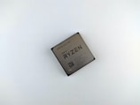 A computer processor with visible branding and specifications printed on its surface. The text includes 'AMD Ryzen 3 3100' along with other technical details and a QR code.