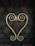Ornamental metal handles with intricate scroll designs form a symmetrical heart shape against a dark, textured door. The door features geometric patterns creating a decorative lattice look.
