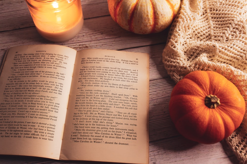 a book and a couple of pumpkins on a table