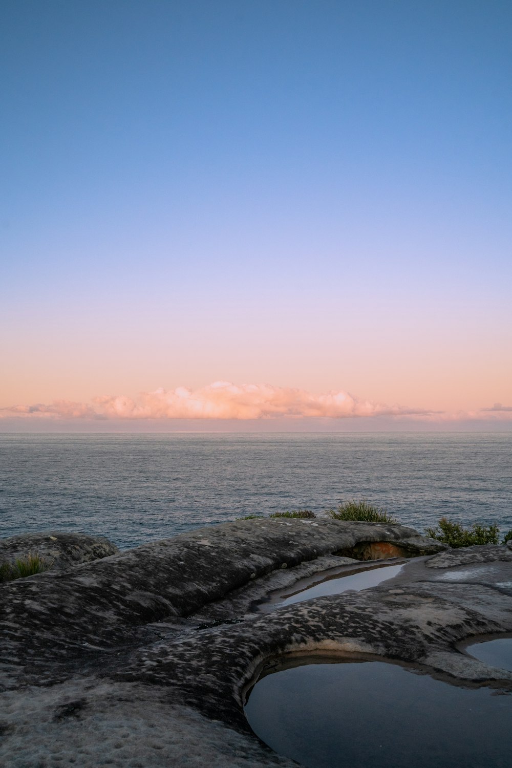 a body of water with rocks and a beach with a sunset