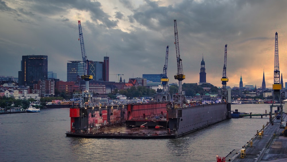 a large ship in the water with cranes in the background