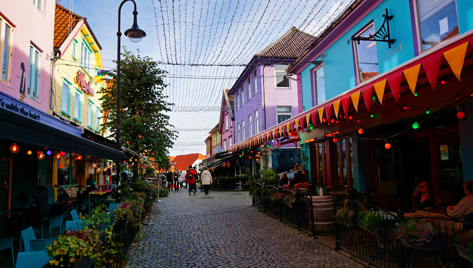 A vibrant street scene from central Brașov with colorful buildings and lively pedestrians.