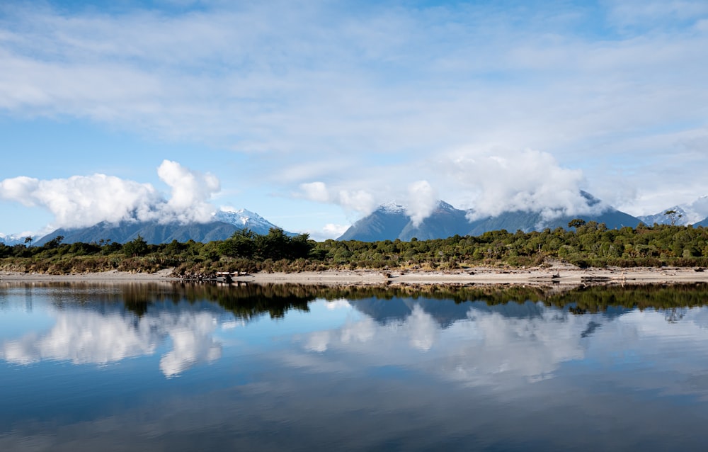 a body of water with trees and mountains in the background