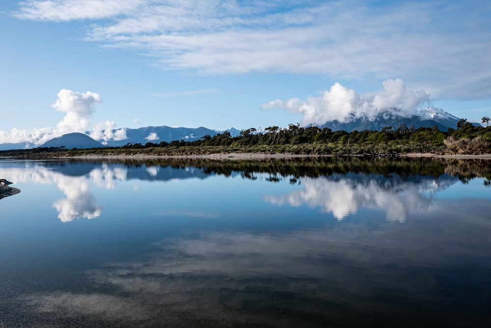 a body of water with trees and mountains in the background