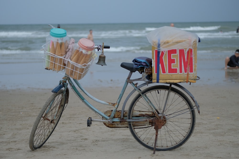 a bicycle with a basket of ice cream on it on a beach