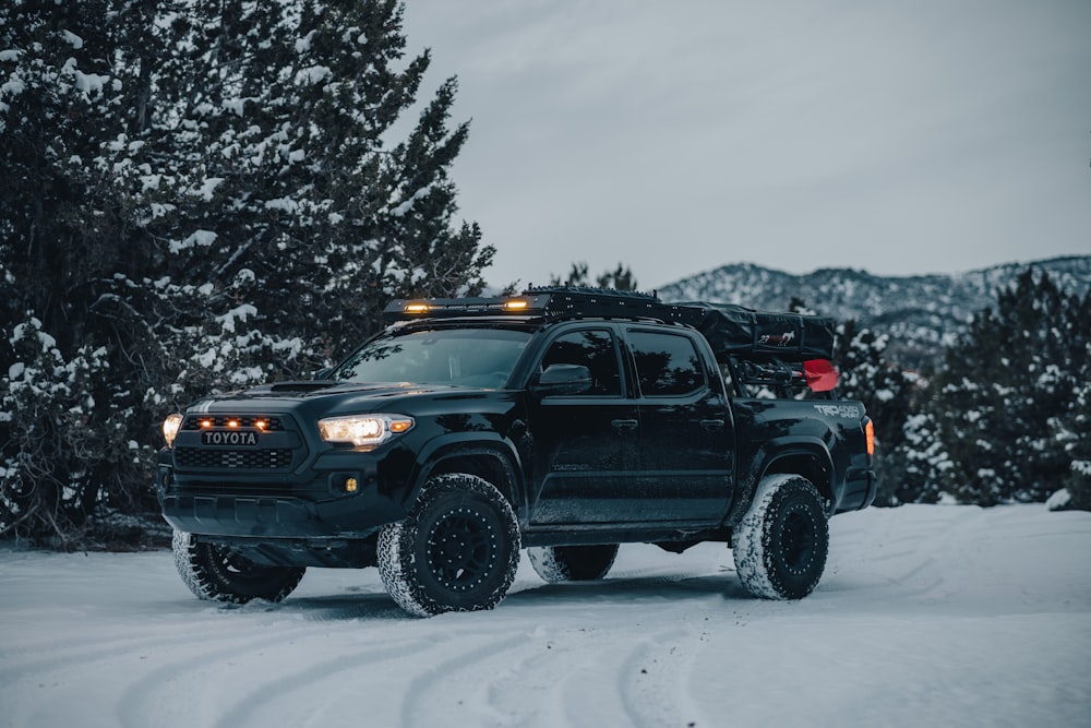 a black truck driving on a snowy road