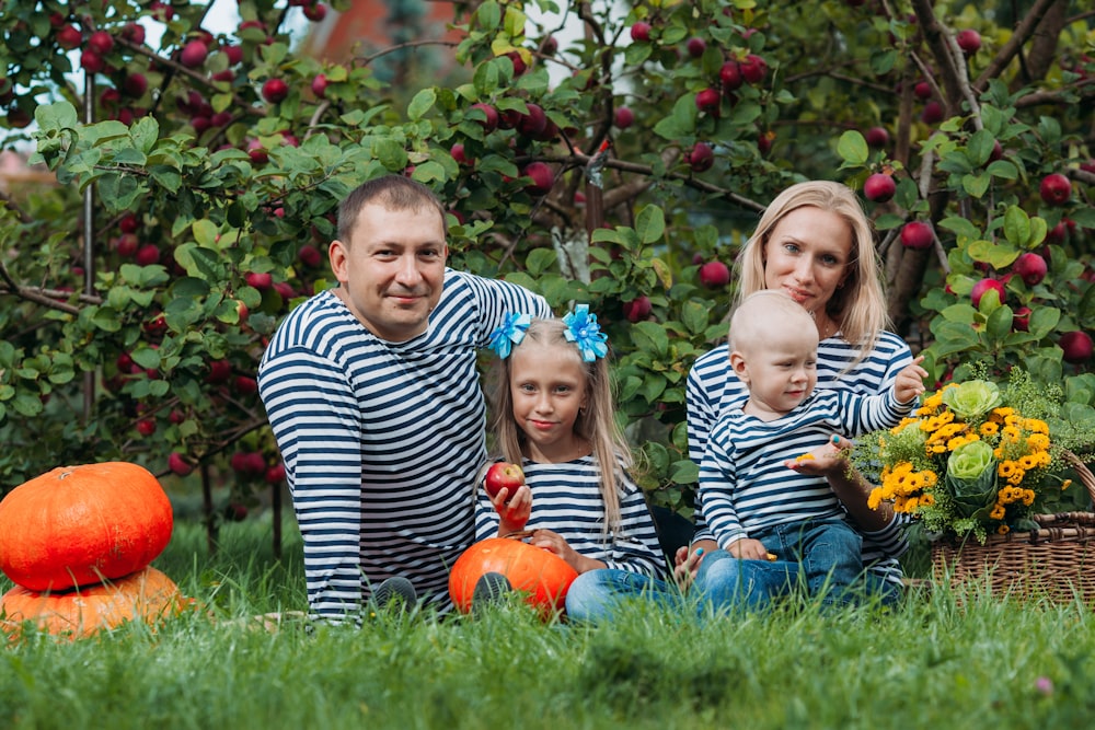 a person and two girls sitting in a pumpkin patch